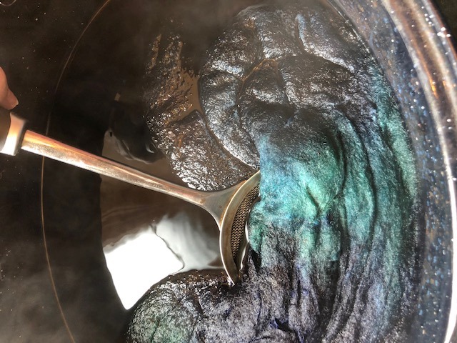 pulling dyed roving out of the dye bath to reveal the color