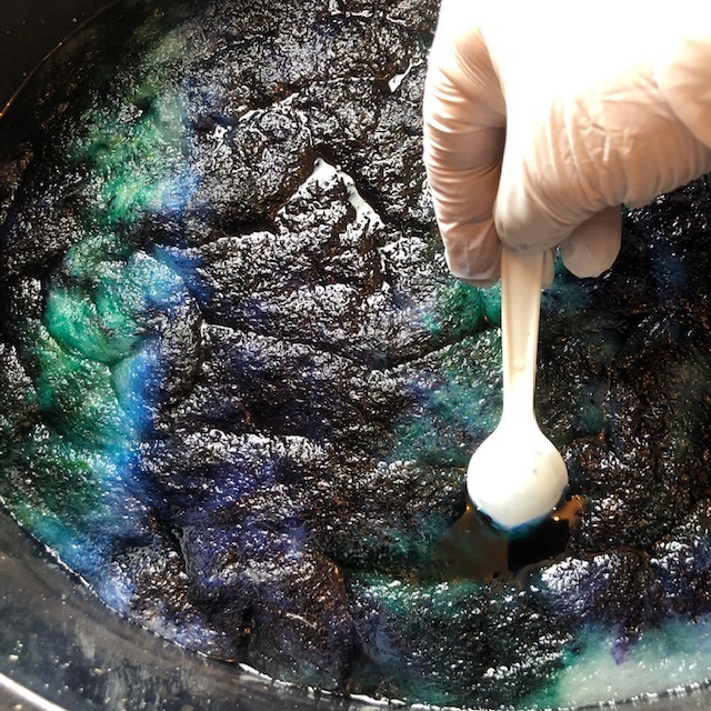 very gently pushing powdered dyes into wet wool for dyeing