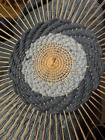 the center of a mandala tapestry weaving, in tan and blues